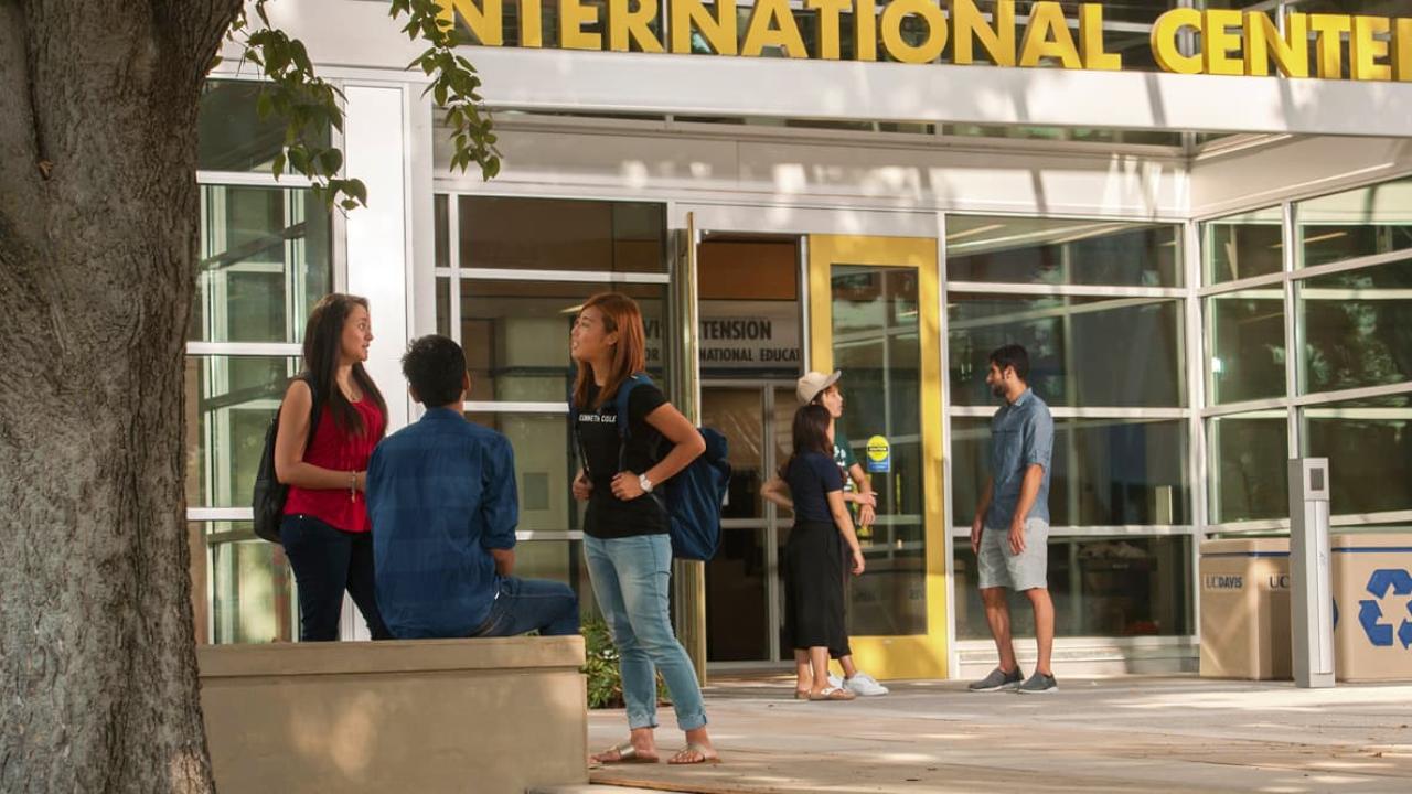 A small group of students talking outside the International Center - International Admission